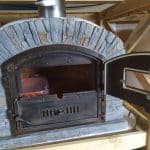 Ventura AL 100 Steinofen mit halb geöffneter Türe und Lager für Spanferkelspieß