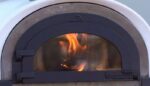 Brennendes Holzfeuer in einem Four Grand Mere Alfred Pizzaofen